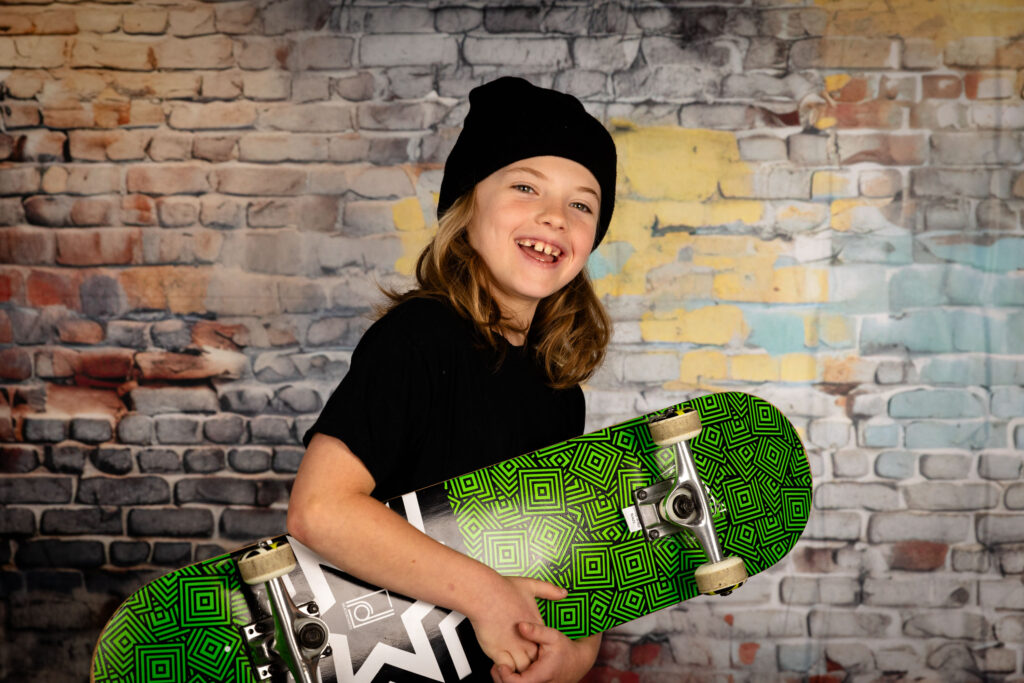 Young boy holding a skateboard.