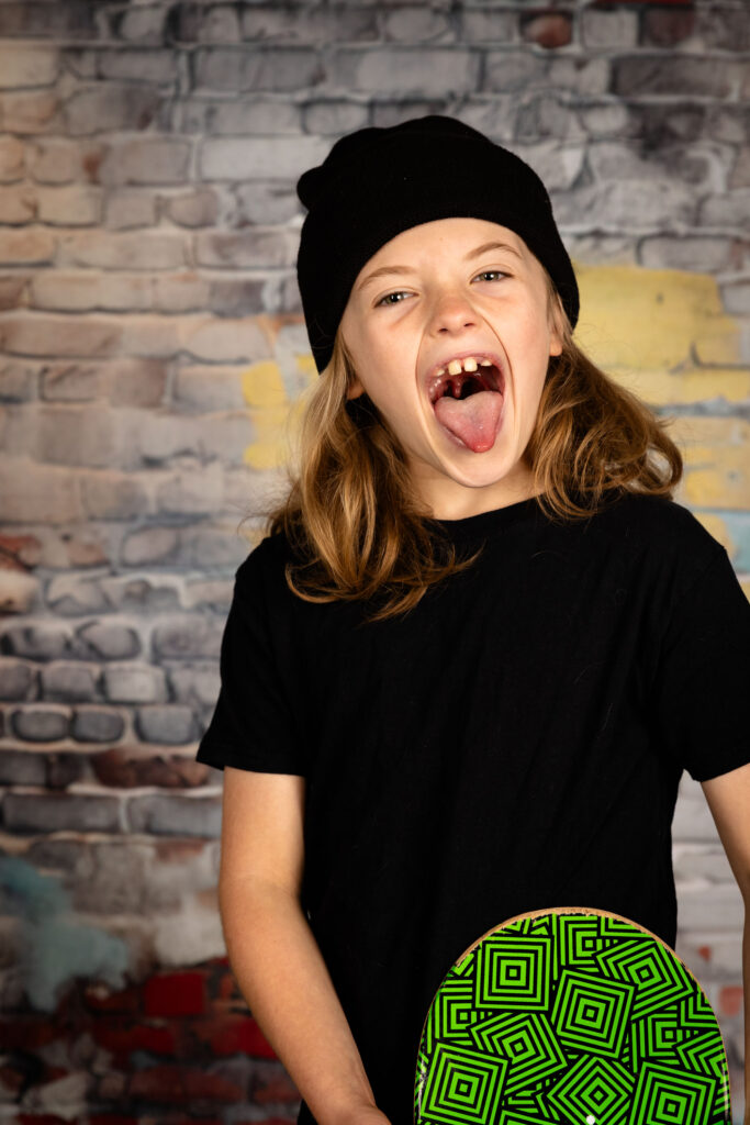 Young boy holding a skateboard while screaming.