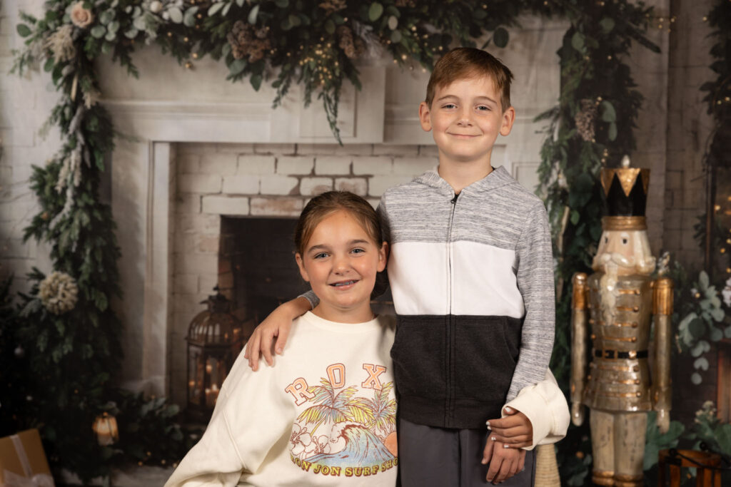 Two siblings smiling standing next to each other.