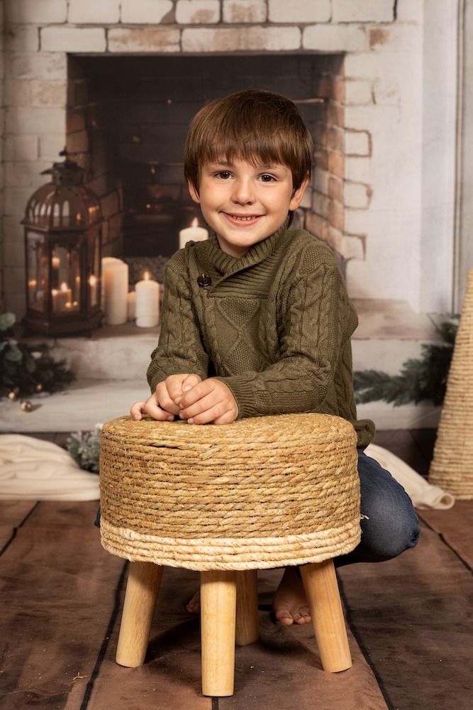 Young boy kneeling on a stool.