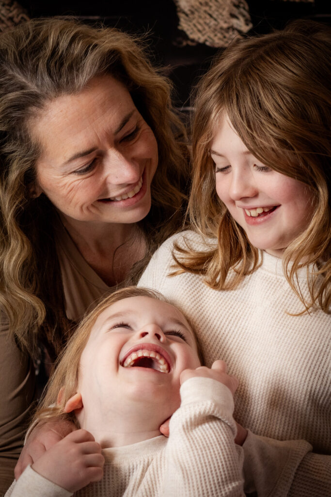 Mom and two young sons laughing at each other.