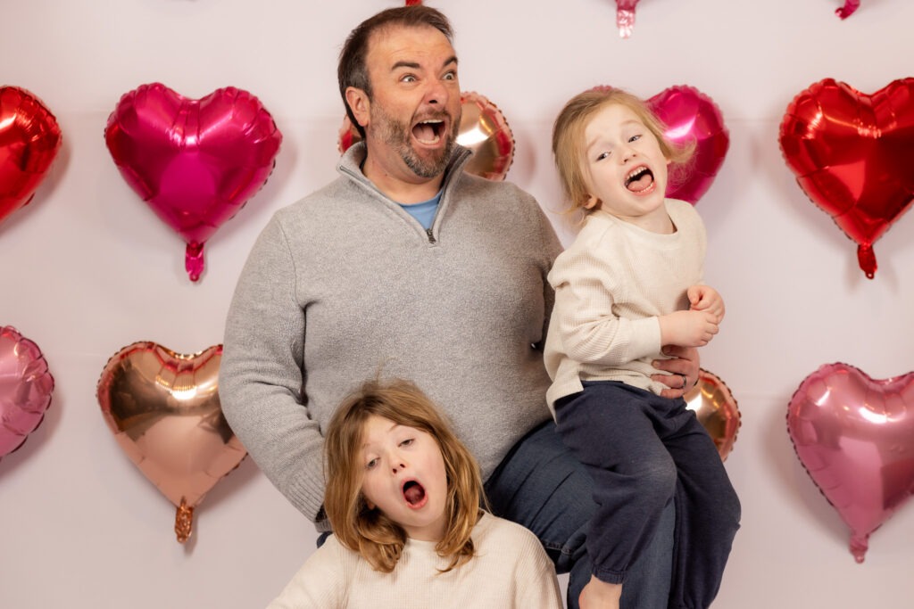 Dad and two young sons making funny faces.