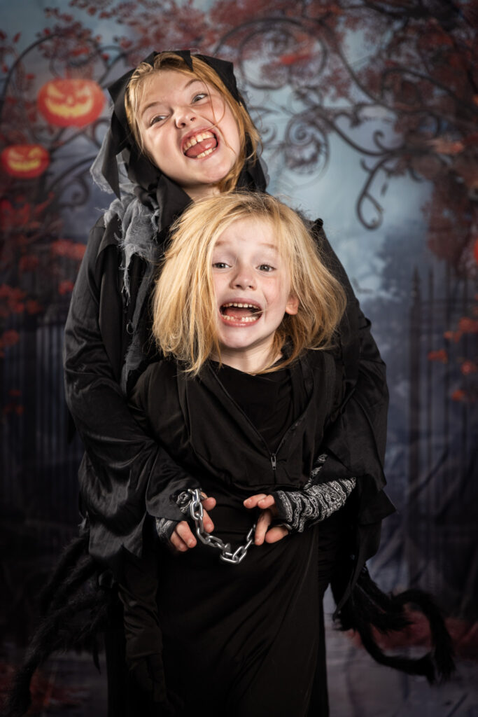 Two boys in dark costumes posing for a scary photo.